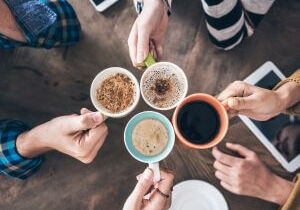 People toasting with coffee cups around a table