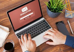 Person typing on a laptop at a wooden desk